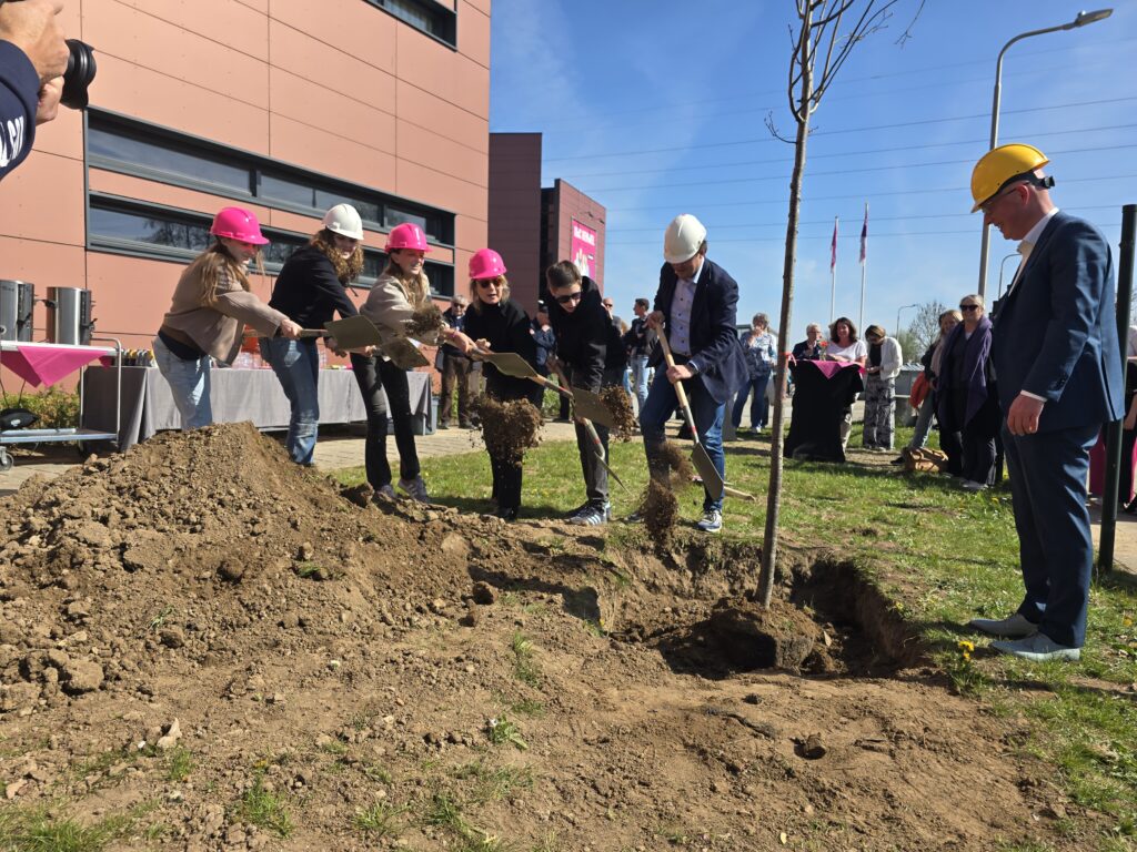 Leerlingen, rector Mascha Schnitzler, wethouder Nick Hubers en Egbert-Jan Rots, directeur van Rots Bouw, planten samen de boom