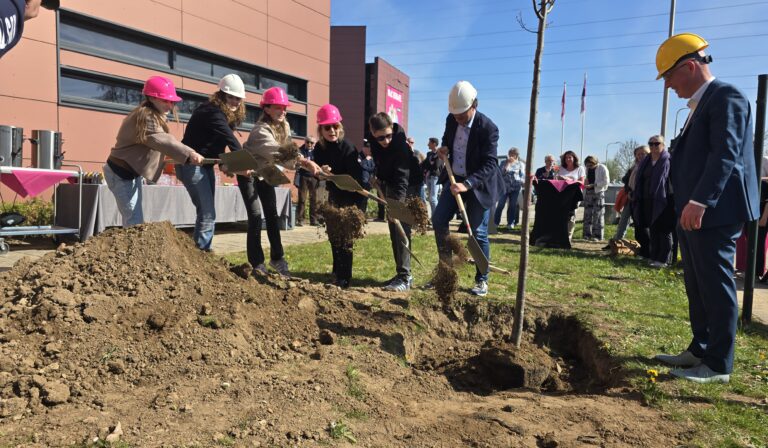 Leerlingen, rector Mascha Schnitzler, wethouder Nick Hubers en Egbert-Jan Rots, directeur van Rots Bouw, planten samen de boom